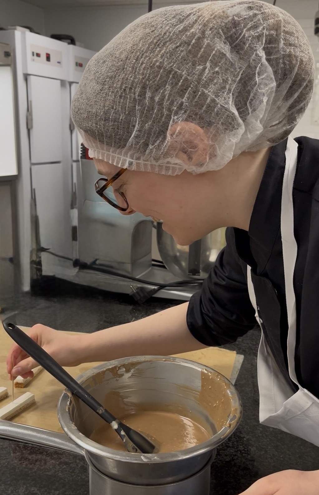 La pâtissière au travail dans son laboratoire, en train de dresser des pâtisseries